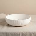 White ribbed ceramic bowl on linen fabric side view